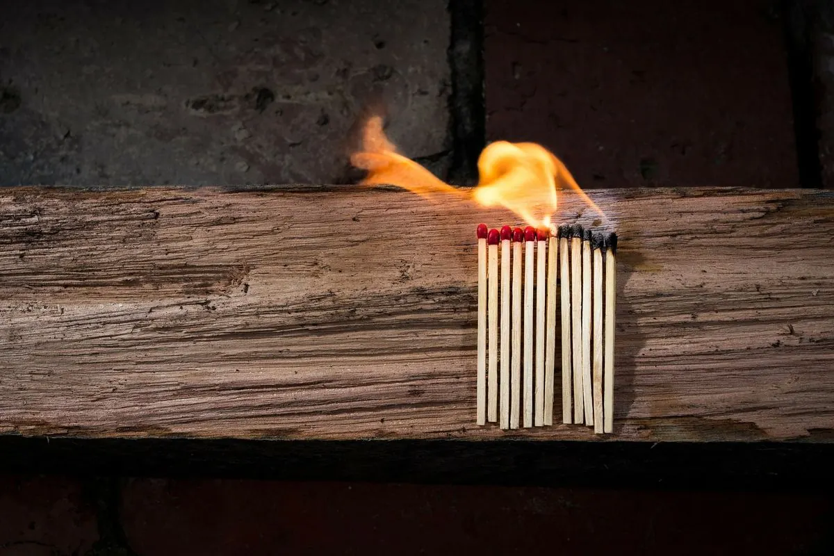Ein Bündel Streichhölzer brennt auf einem alten Holzbalken