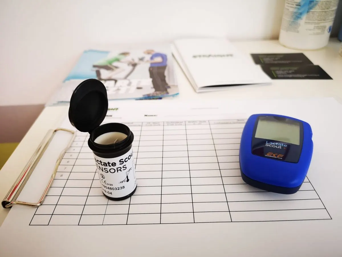 Laktat-Messgerät, Teststreifen und Messprotokoll auf dem Tisch