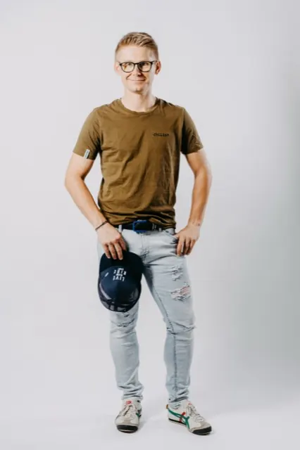 Mario Einödmaier lächelt im Studio in die Kamera, eine Kappe in der Hand